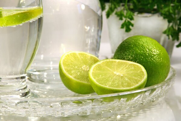 On a glass tray are lime and a glass