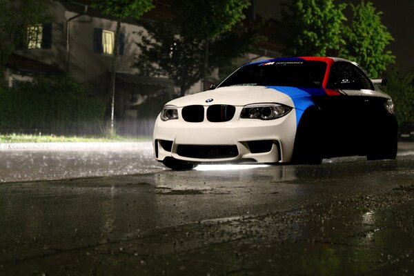 BMW a strisce sulla pioggia della città di notte