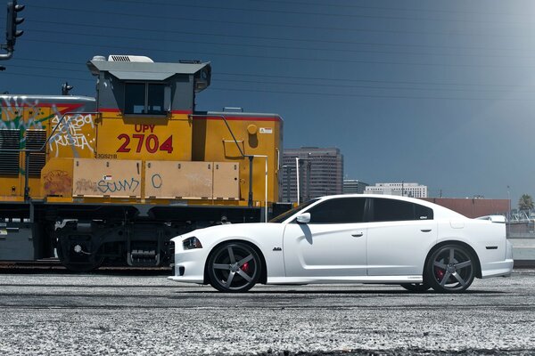 Une Dodge teintée se tient près du train