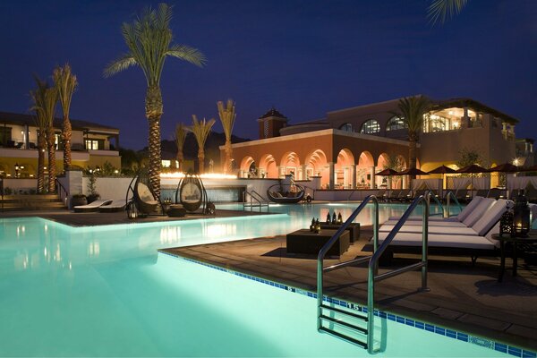 Illuminated pool with palm trees in the evening