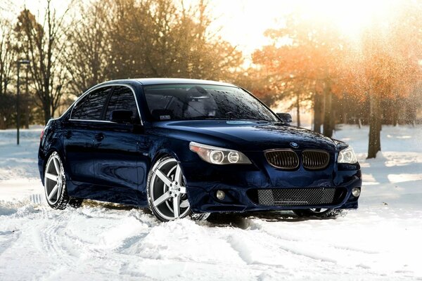 A dark blue car on the street is the winter time of the year