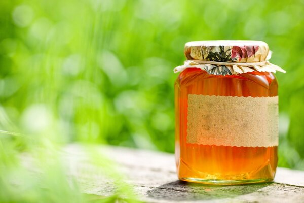 A jar of liquid honey on a checkered table