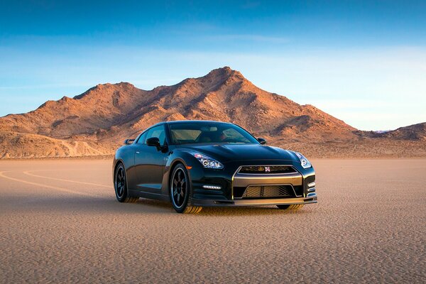 Ein schwarzer Nissan inmitten der Wüste und der Berge