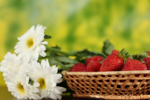 Strawberries in the basket. Next to a bouquet of daisies