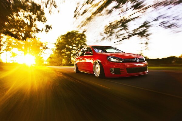 Volkswagen golf rouge sur fond de lumière du soleil en mouvement