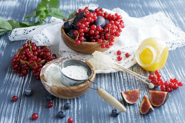 Auf dem Tisch liegen rote Johannisbeeren, Honig, Feigen, Mehl