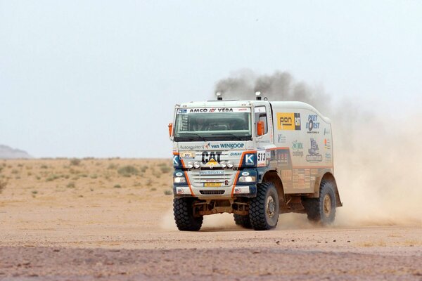 Un camion da corsa cavalca un palo di polvere nel deserto