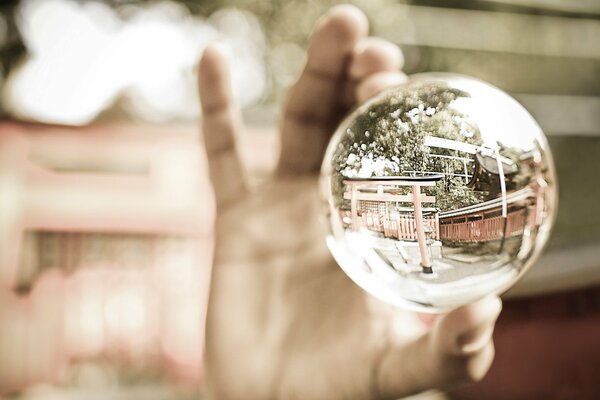 The hand holds a ball in which the street is reflected