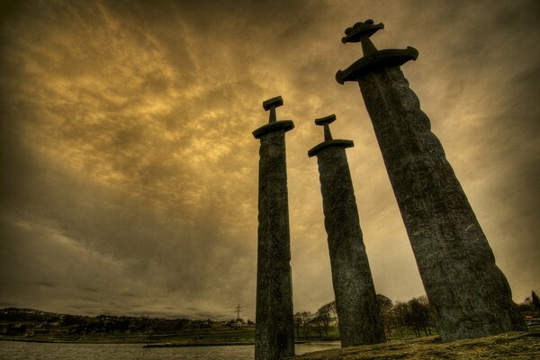 Tres espadas de piedra contra el cielo ardiente