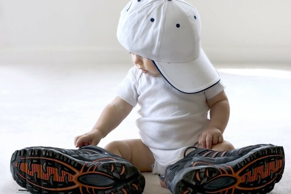 Bébé dans une casquette et de grandes baskets