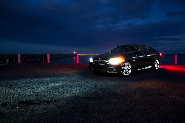 Black bmw f10 on the night pier