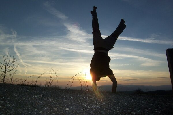 Coucher de soleil illumine un homme debout sur ses mains