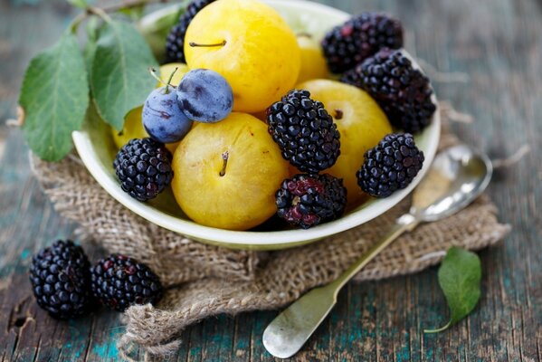 Beeren, Pflaumen in einem Teller. Neben dem Löffel