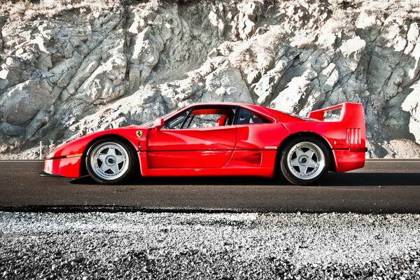 Roter Sportwagen der Marke Ferrari auf dem Hintergrund der Felsen