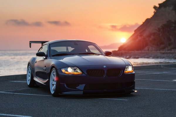 Coche bmw z4 al atardecer en la orilla del mar