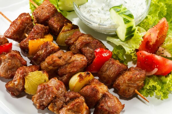 Serving shish kebab with vegetables and sauce