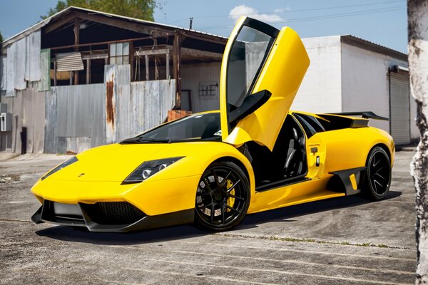 Gelber Lamborghini murcielago auf dem Hintergrund einer alten Scheune