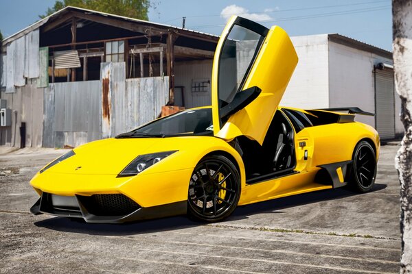 Жёлтый lamborghini murcielago на фоне старого сарая