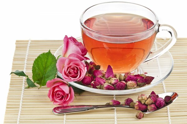 Thé dans une tasse en verre sur fond de roses