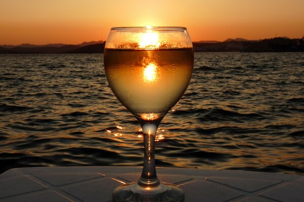Vista de la puesta de sol a través del prisma del agua en una Copa de vino