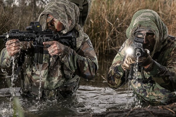 Men in military uniforms come out of the water