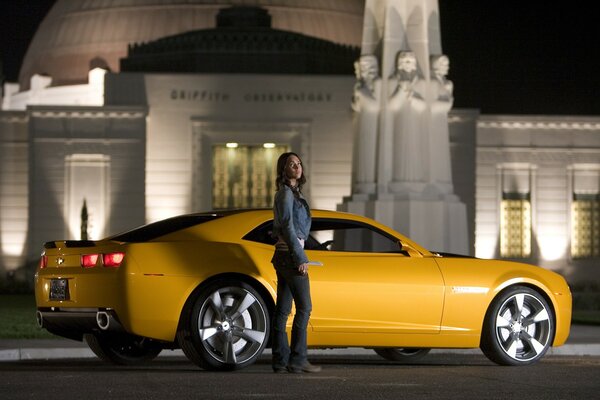 Megan Fox aus dem Film Transformers mit einem gelben Auto