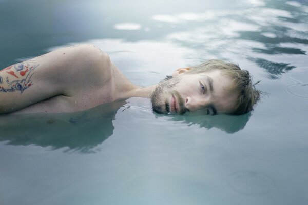 A man lying in the water with a tattoo