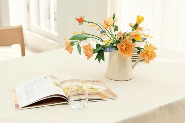 Auf dem Tisch liegt eine Vase mit Blumen und ein offenes Buch