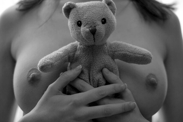 Mädchen mit entblößten Brüsten drückt einen Teddybären an sich