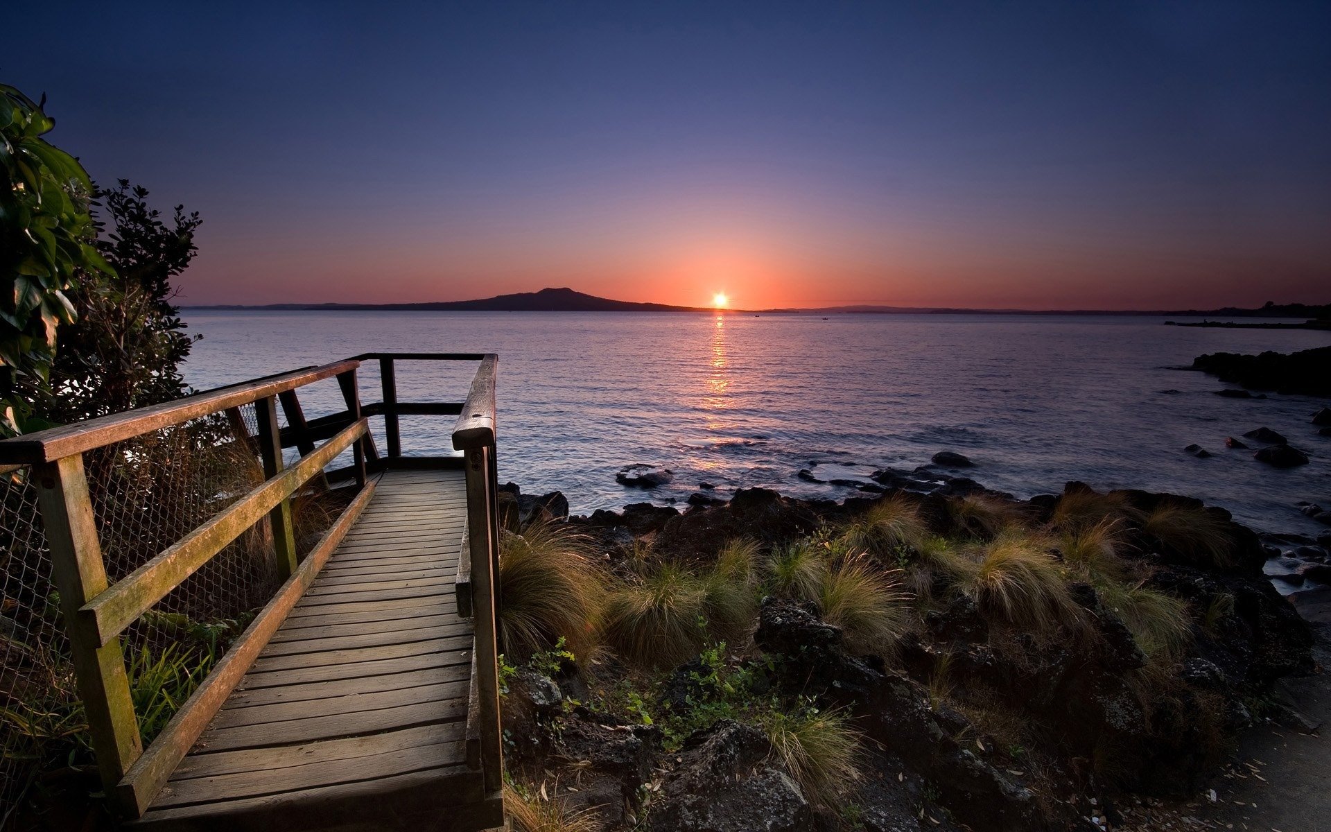 beach rails stones water sun sunset