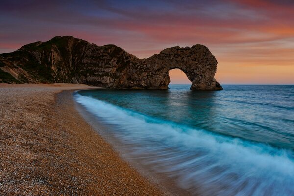 Plage du soir, arche dans la mer de la falaise