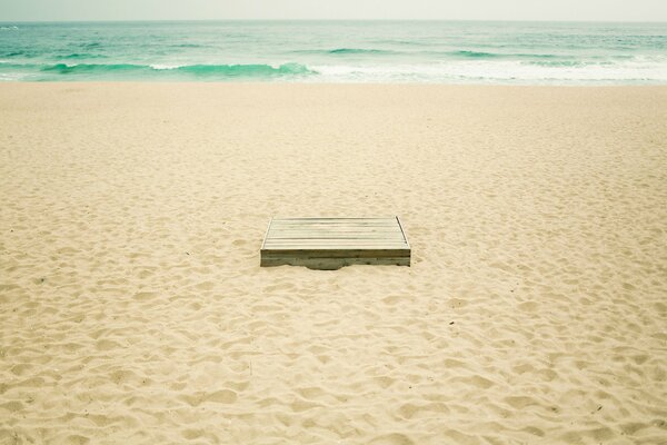 Boîte sur la plage de sable jaune. Vagues turquoises