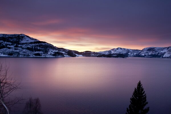 Purple lake on the background of snow-capped mountains in the sunset light