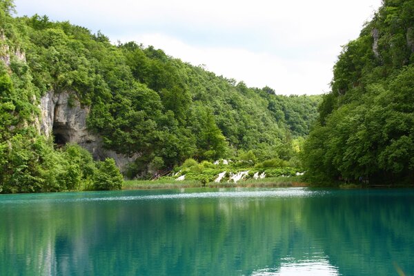 Nature on the shore of a turquoise lake with steep green rocks