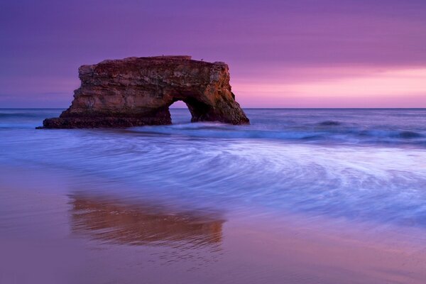 Rocas en el mar en una puesta de sol rosa