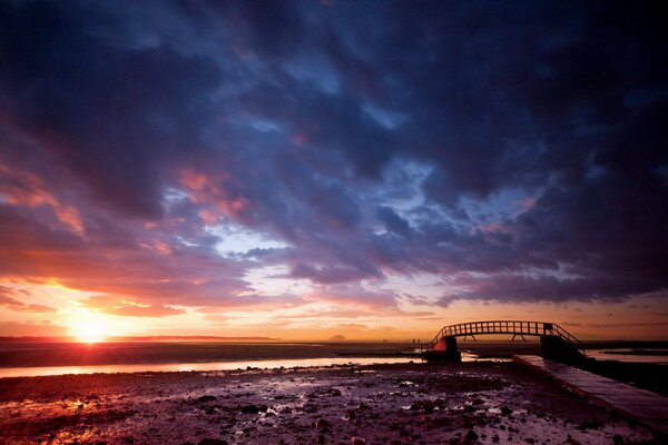 View of the bridge against the sky where the sun is setting on the horizon