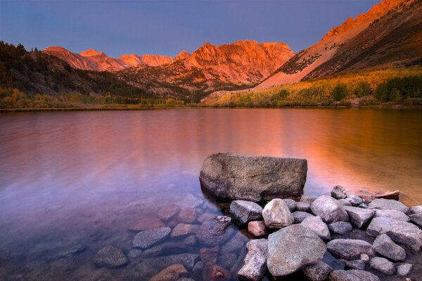 Lac propre parmi les montagnes au coucher du soleil