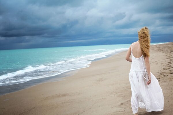 Ragazza solitaria in abito bianco in riva al mare