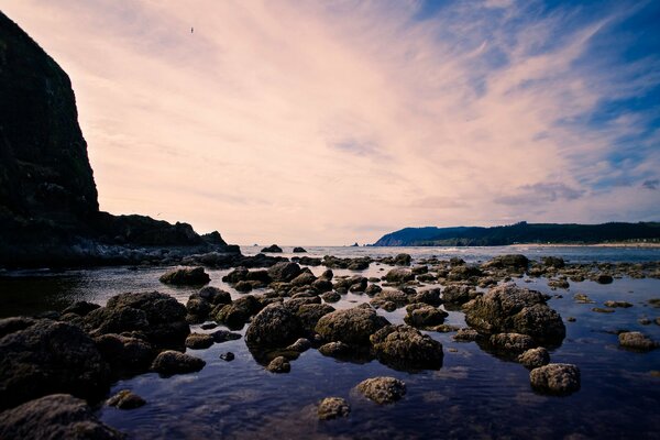 A lot of stones in the water against the background of mountains and sky