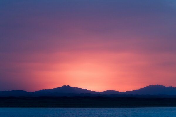 Tramonto malva e sagome di montagne