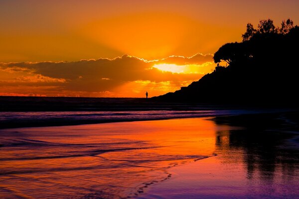 Sonnenuntergang am Strand mit einem Mann in der Ferne