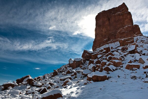 Una roca en un pico nevado contra un cielo azul