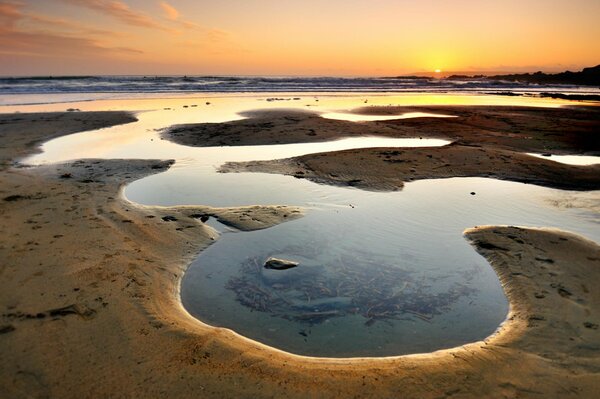 Water in sand bowls at sunset