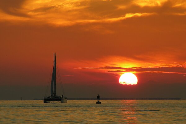 Puesta de sol y boya visible y catamarán