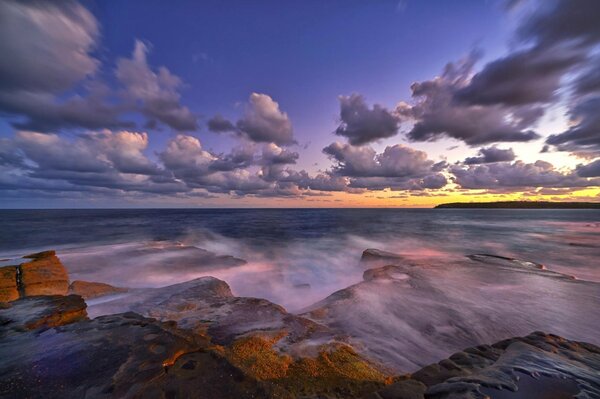 Stone seashore and sunset sky with clouds