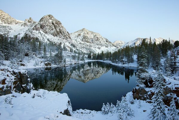 Paisaje invernal: lago, cielo, montañas y bosque en tonos blancos y azules