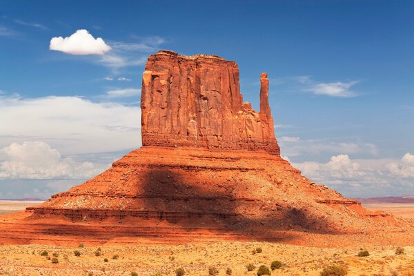 A lonely rock in the desert with a blue sky