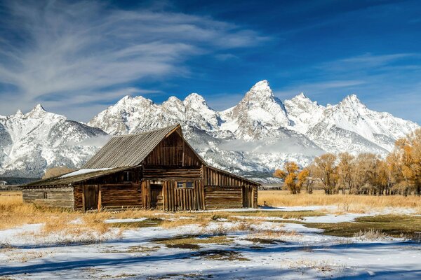 An old hut on the background of snow-capped mountains