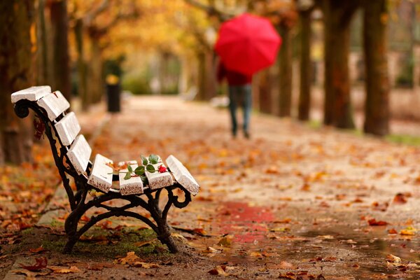 Un hombre que se va con un paraguas en un parque de otoño