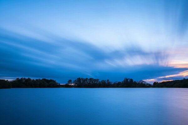 The forest separating the night sky and the quiet surface